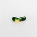 Green capsule split open with golden powder spilling out, representing dietary supplement ingredients.